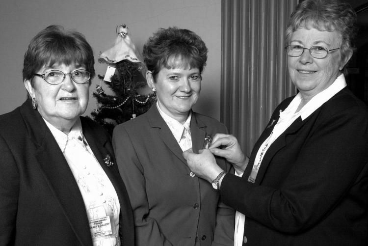 Patricia Roy-Ballem, (right), PEI Advisory Council on the Status of Women chairperson, pins a purple ribbon on Pat Mella, Provincial Treasurer, and Minister Responsible for the Status of Women with Inge Blackett, vice-chairperson (left), 1999 / B. Simpson Purple Ribbon campaign photo 1999