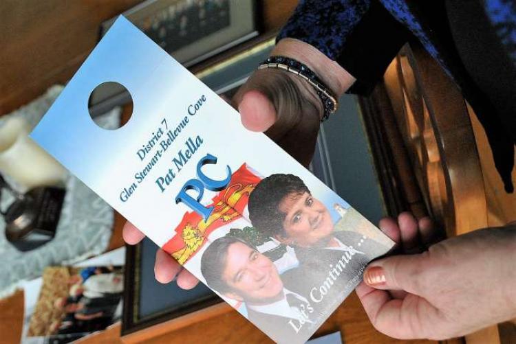 Sample of Mella's election campaign materials /N. MacPhee Pat Mella holds a sample door knocker from the provincial election campaign of 1996 /N. MacPhee